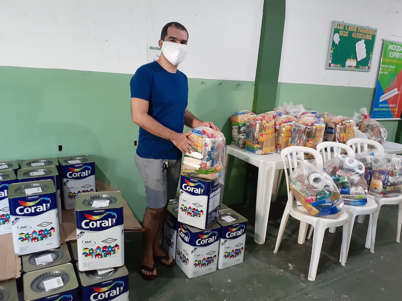 Homem recebendo em mãos as arrecadações de alimentos em parceria com as Tintas Coral.