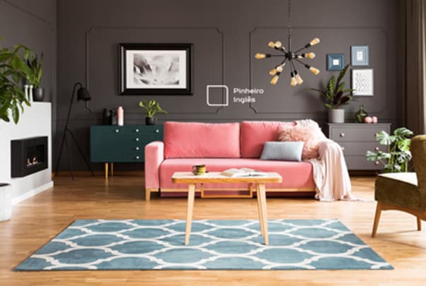 Combinar a cor do sofá com a tinta da parede é uma escolha certeira para uma decoração estilosa. Veja como a cor Pinheiro Inglês que é um tom mais intenso de marrom casa bem com o móvel central da sala que é um sofá rosado. Lindo esse ambiente com as cores da Tintas Coral. 