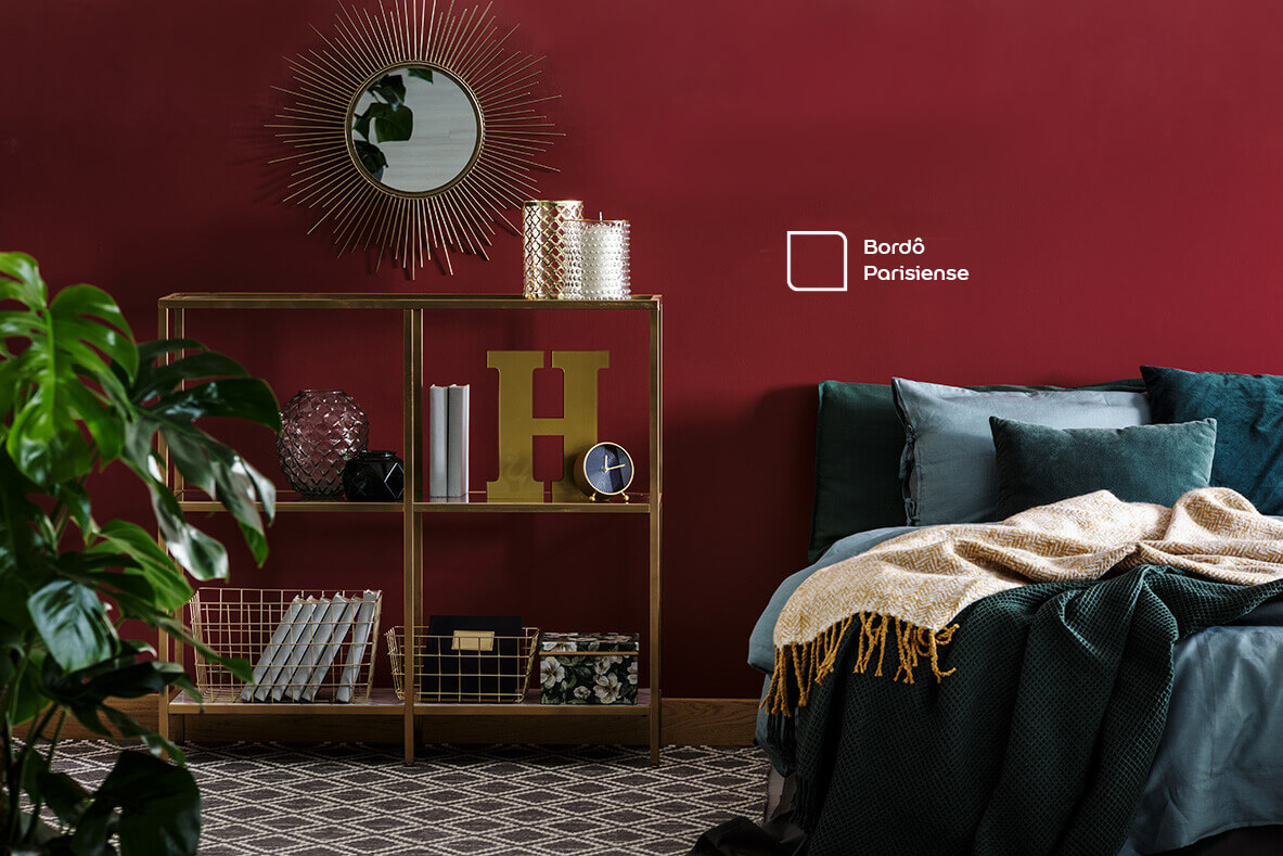 Quarto com parede em destaque na cor Bordô Parisiense da Tintas Coral. A cor intensa do vinho gera personalidade ao ambiente e combina com a coloração azul da cama.