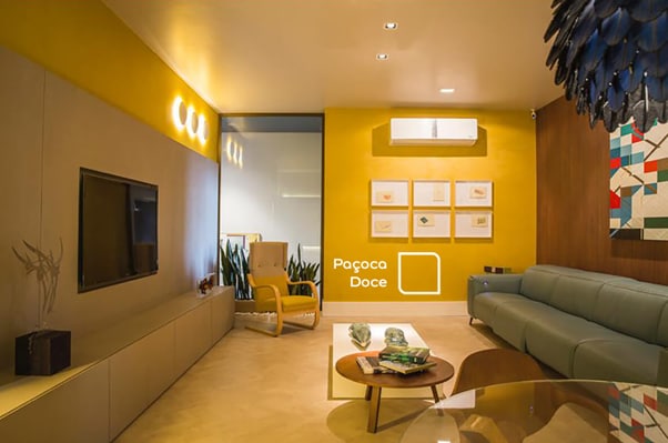 Sala de estar com parede em destaque na cor Paçoca Doce da Tintas Coral. Cores fortes combinam com tons neuros para harmonizar o ambiente. 