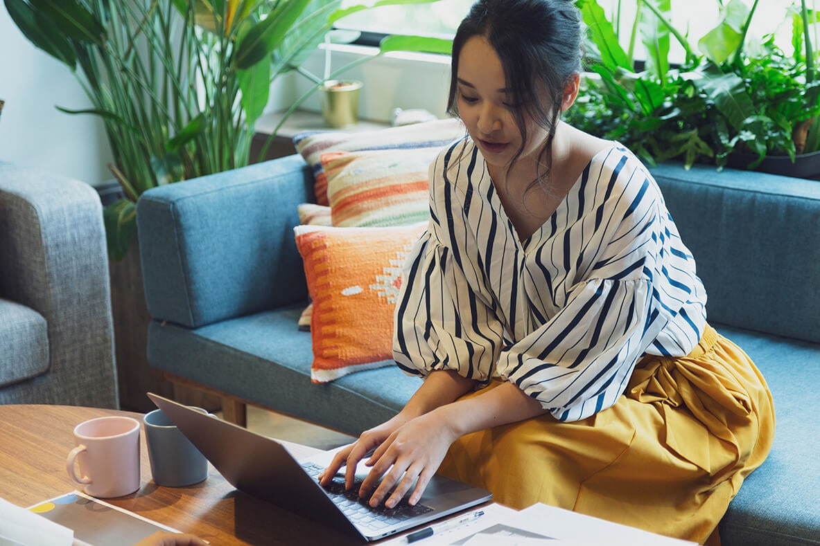 Mulher sentada no sofá trabalhando no home office com seu notebook