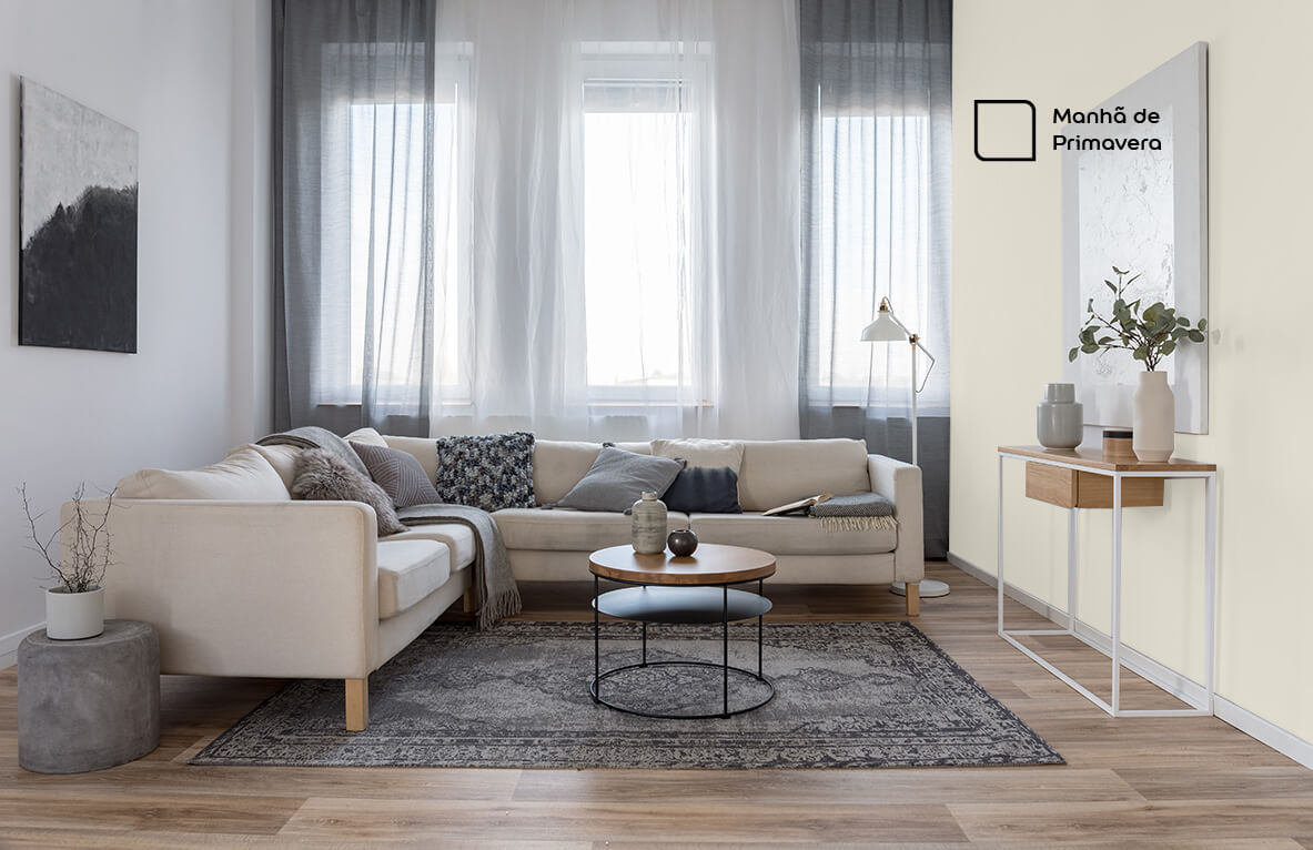 Sala de estar renovada com a cor Manhã de Primavera da Tintas Coral. A tonalidade bege combinou super com o tapete em cinza e os móveis de madeira.