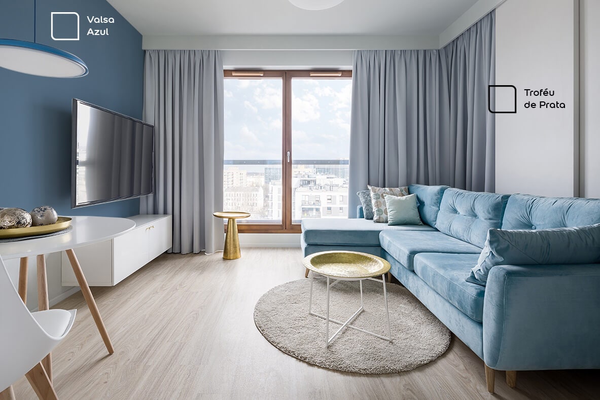 Sala de TV renovada com a cor Valsa Azul da Tintas Coral. Essa tonalidade super combinou com o sofá azul claro e a cortina cinza.