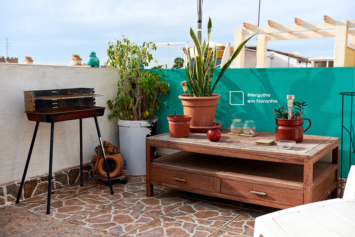 Varanda Gourmet renovada com a cor Mergulho em Noronha da Tintas Coral. O tom de verde combina perfeitamente com o estilo do local, formado com a churrasqueira e o móvel de madeira   