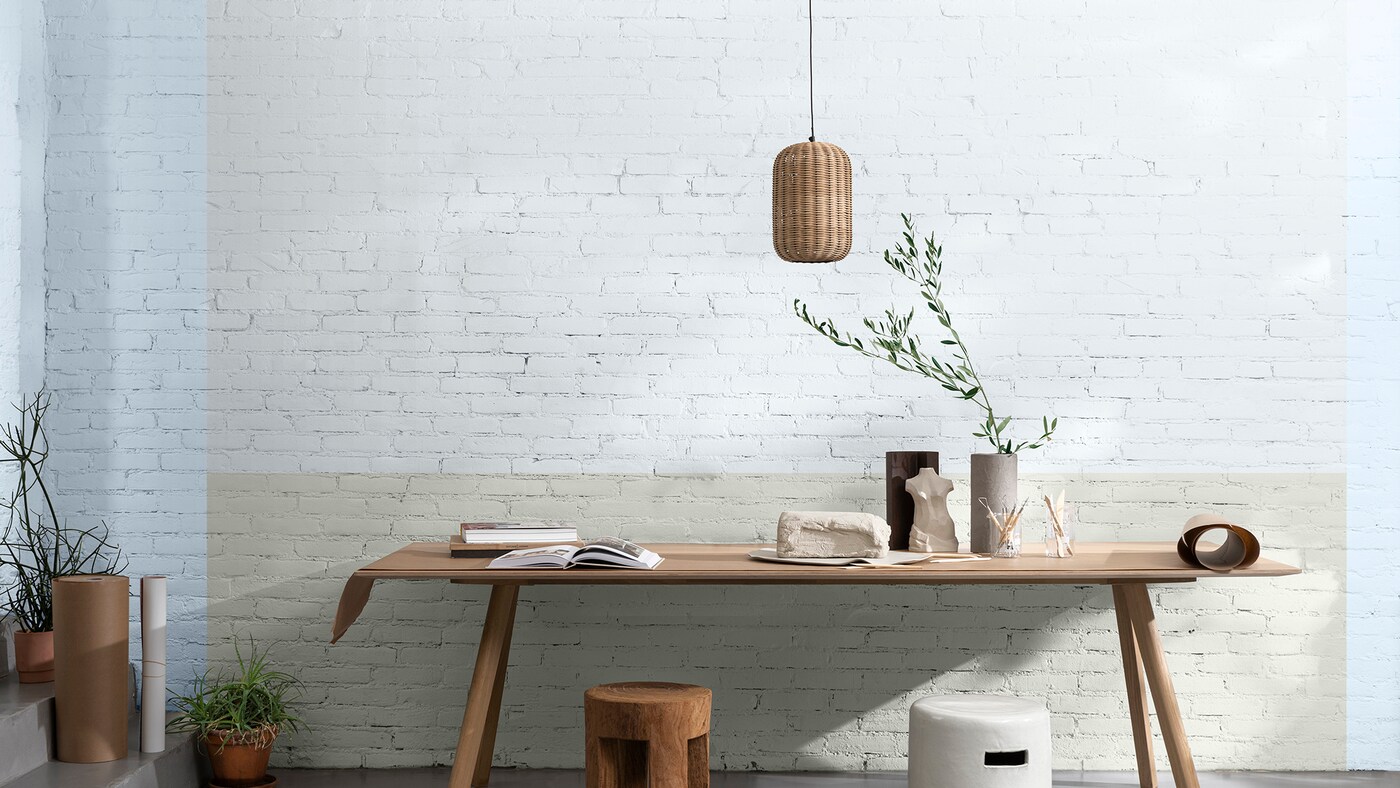 书桌倚靠在带蓝色边框的淡绿色砖墙上