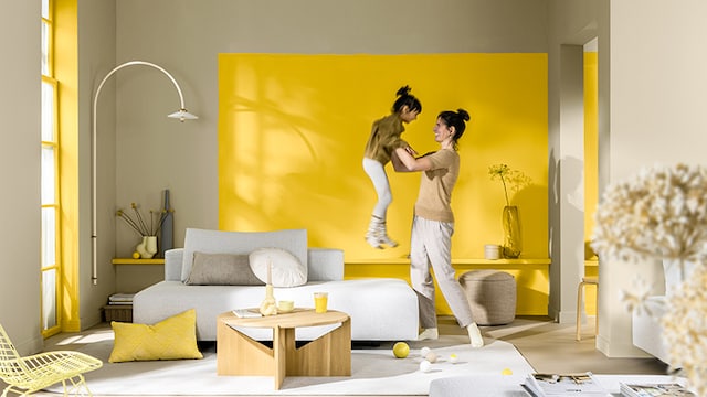 兩位女生在客廳中跳舞，客廳牆面呈現三種不同的藍色。