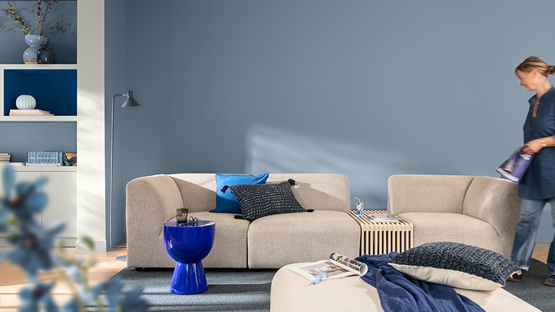 Living room with beige sofa and blue wall, stool and cushions