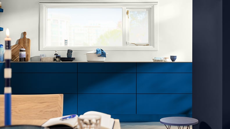 Blue-painted kitchen units against a white wall
