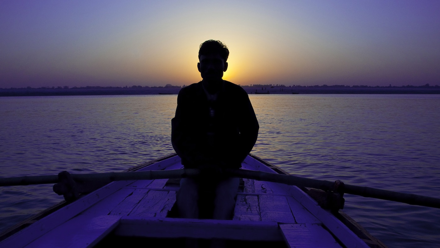 Person rowing on a lake beneath a calming purple sky.