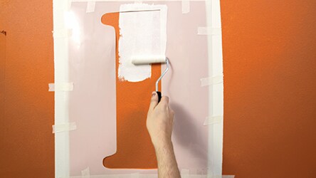 Przyklej do ściany szablony malarskie i pokryj ich wnętrze farbą Nieskazitelna Biel.