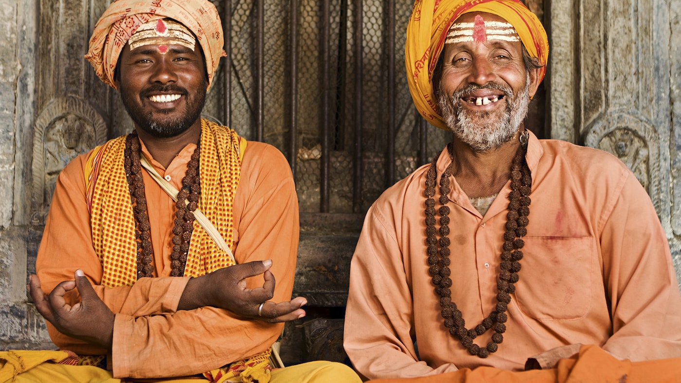 Two Indian men dressed in orange clothes socialize together.