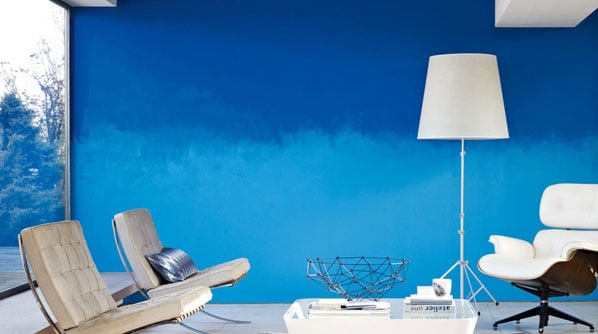 Light and dark shades of blue paint create the ombre effect on a living room wall.
