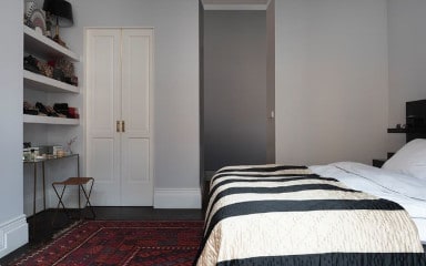 Light Grey Bedroom With A White And Black Patterned Bed And White Shelving 