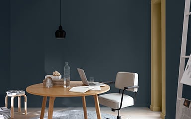 dark blue wall with a round table and small black lampshade