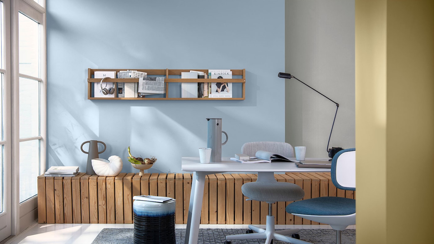 A workspace with a feature wall painted in a pastel blue against a window.