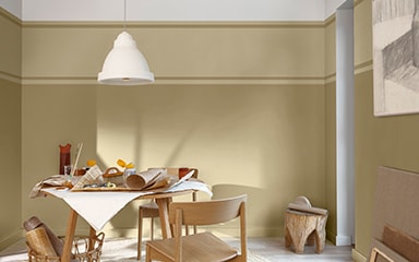 A two tone wall with a round table and white lampshade