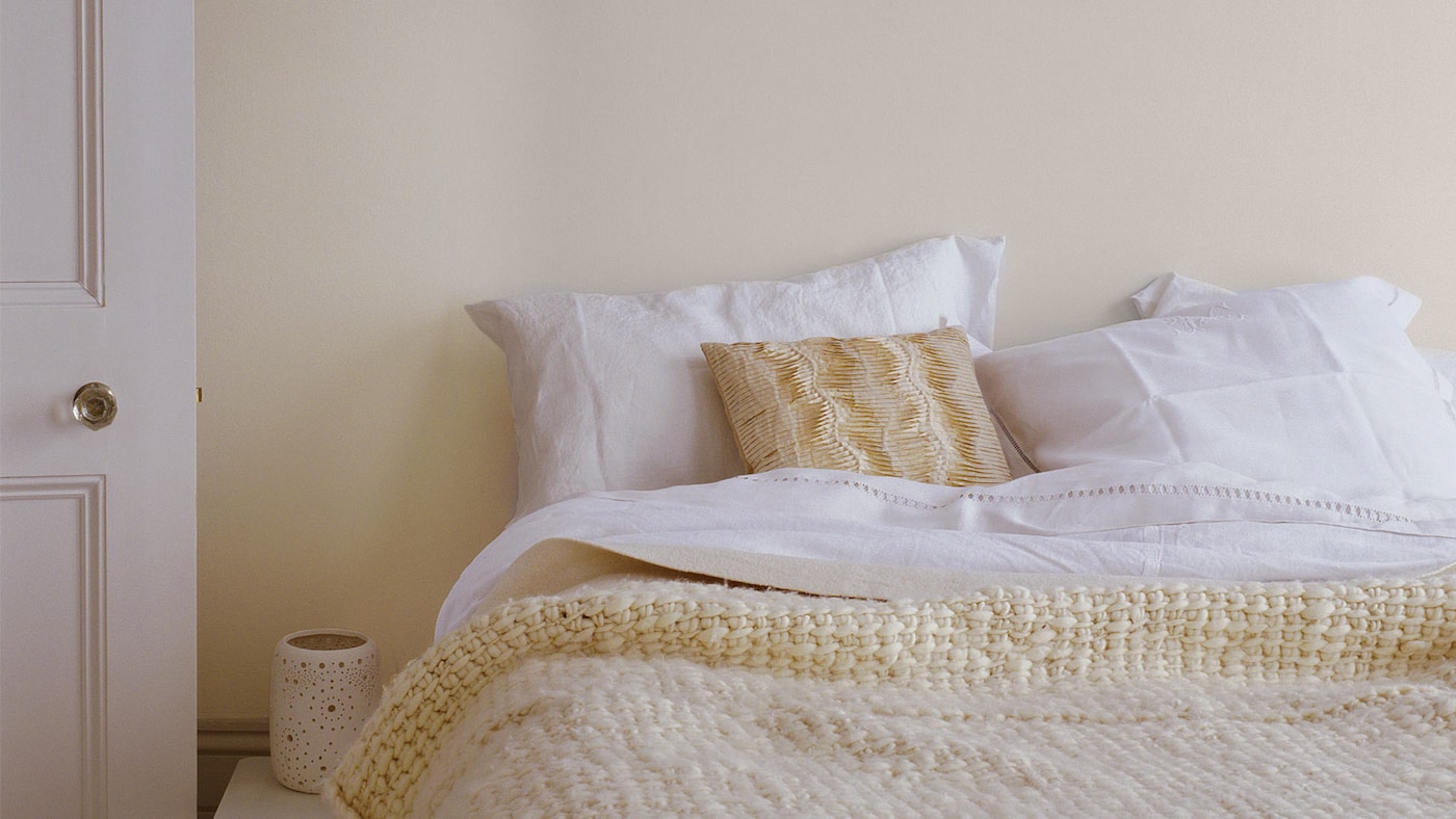 Lit avec couvre-lit ton crème et mur ton crème