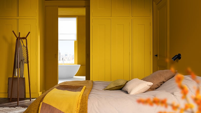 Slaapkamer met bed en gele muur.