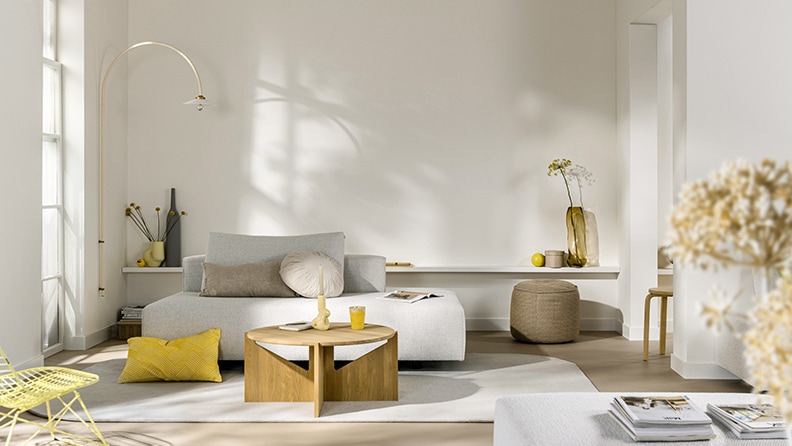 Woonkamer met een witte muur en meubels met geel tinten.