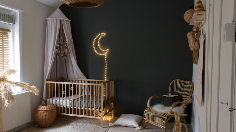 De stoere donkergroene babykamer gecombineerd met rotan en een zandkleur. 