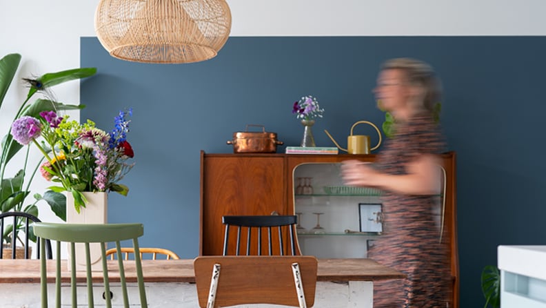 Faded Indigo op de muur bij de eethoek met vintage meubels en planten