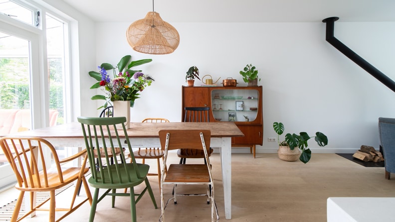 Eethoek met grote tafel, vintage stoelen en een jaren 60 wandkast.