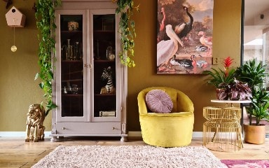 Gele stoel naast een beige kast voor een okergele muur