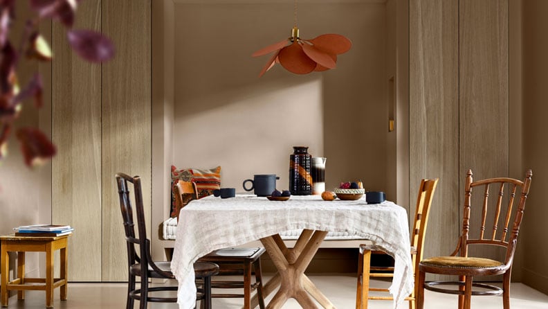 een eetkamer met muren in de kleur Brave Ground