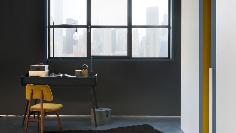 zwarte woonkamer met oker stoel