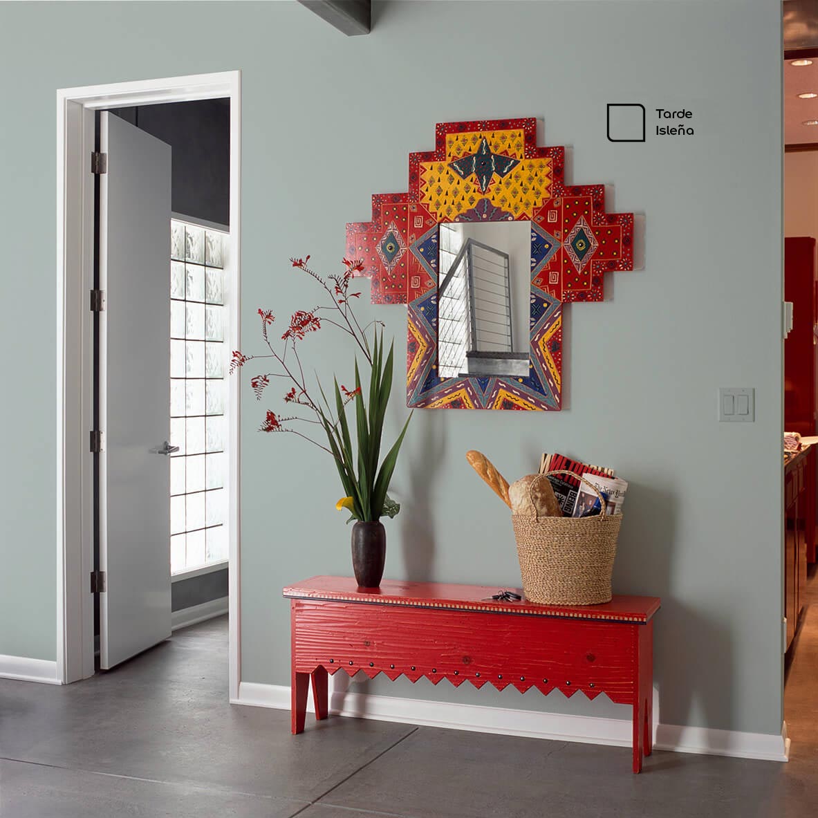 Recibidor decorado con una pared pintada en el color Tarde Isleña de Inca. El uso del espejo es una forma creativa de desviar la atención de las paredes.