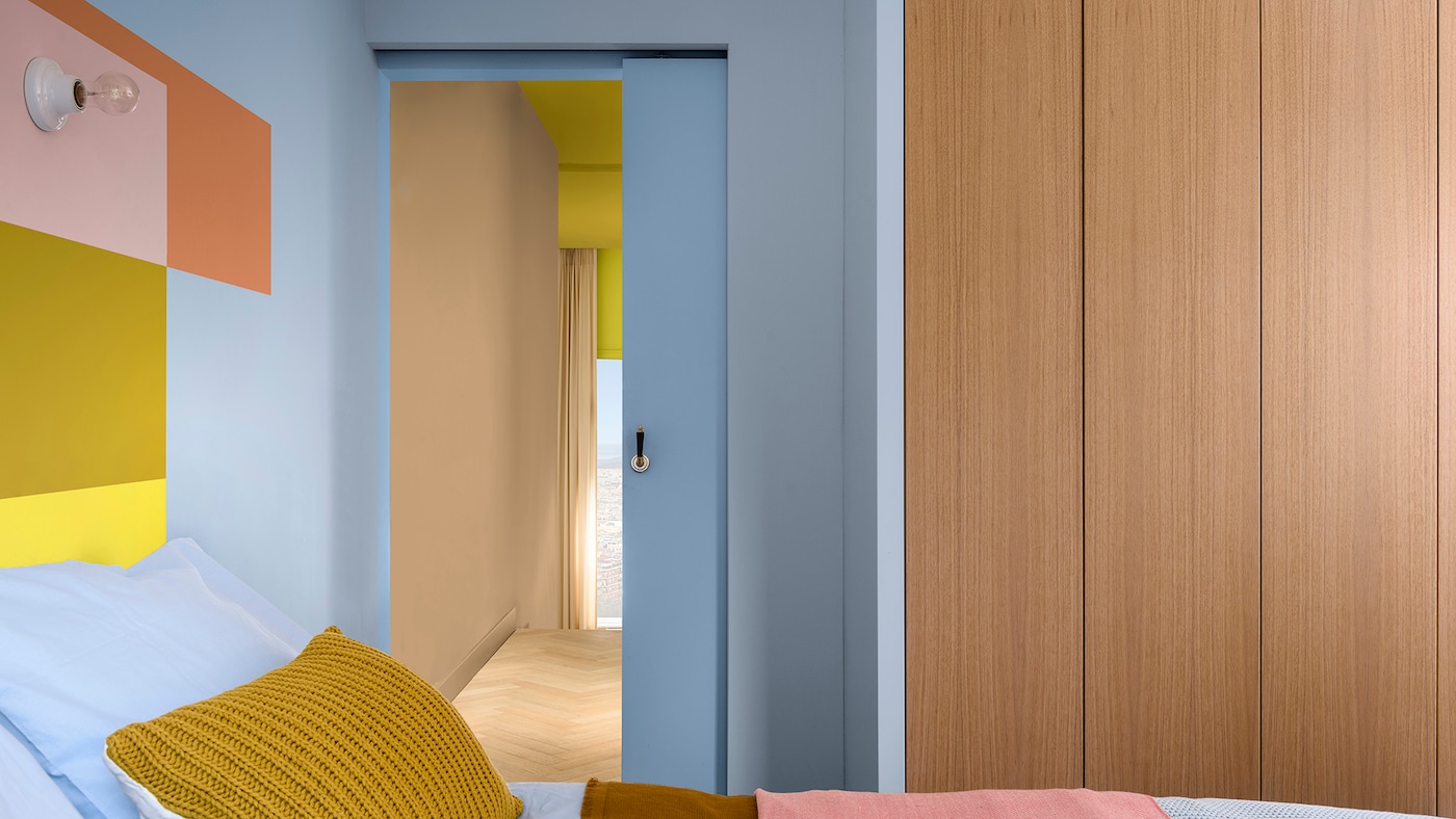 Slaapkamer in lichtblauw met geverfde blokken bij het hoofdeinde