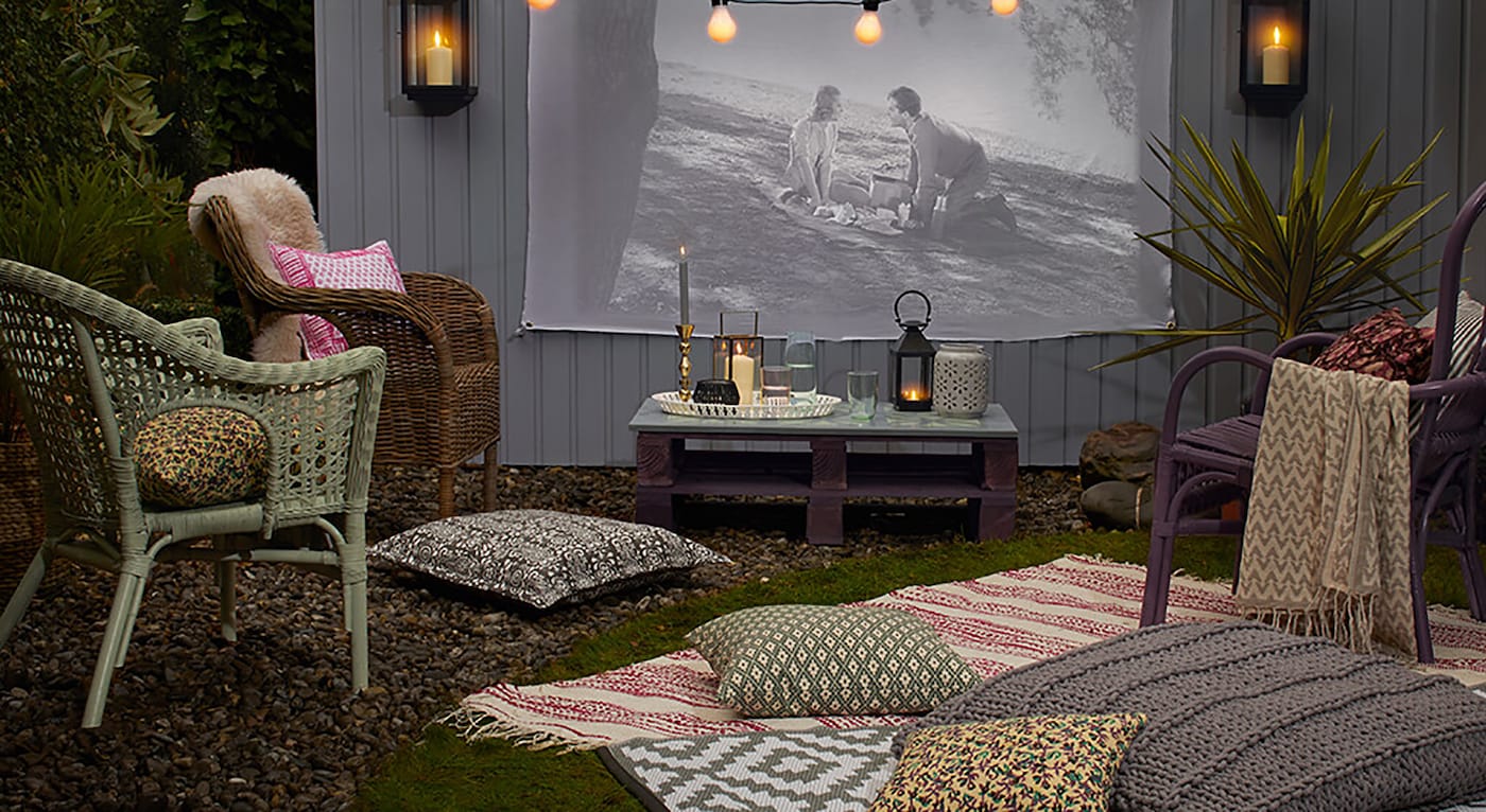 Hageparty med film i hagen mot gråmalt vegg