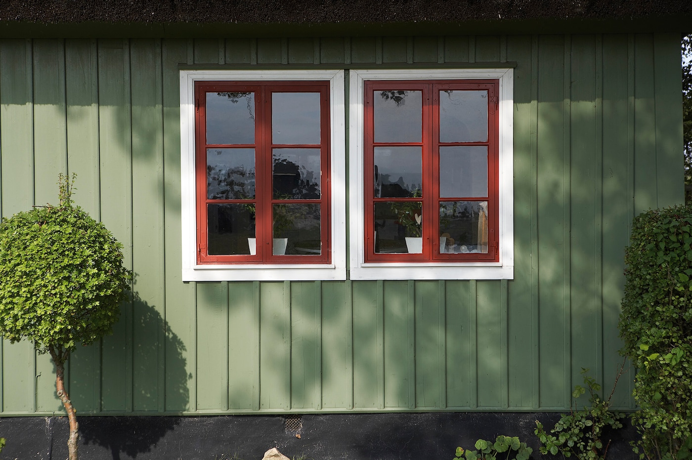 Fasaden er malt med grønn eksteriørmaling og hvite og røde vinduskarmer