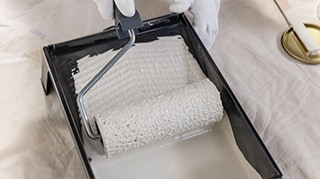 O perosană care se pregătește să aplice cu trafaletul  vopsea lavabilă savana.