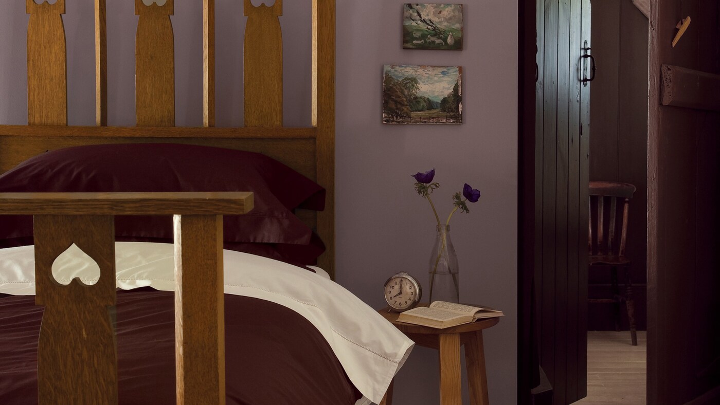 Purple walls bring warmth and nostalgia to this comfortable bedroom.
