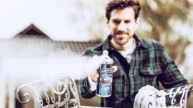 Ein Mann sprüht Metall-Schutzlack von Hammerite aus einer Sprühdose auf ein Metallobjekt auf.