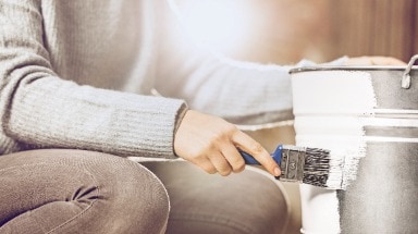 Eine Frau streicht einen Eimer mit dem Metall-Schutzlack Ultima von Hammerite.