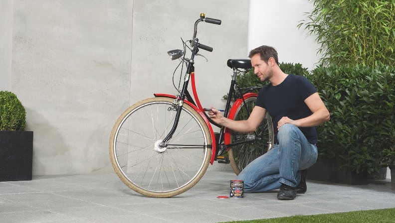 Ein Mann streicht ein Fahrrad mit Metall-Schutzlack von Hammerite