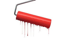 Red paint roller with metal handle dripping bright red paint against a white background.