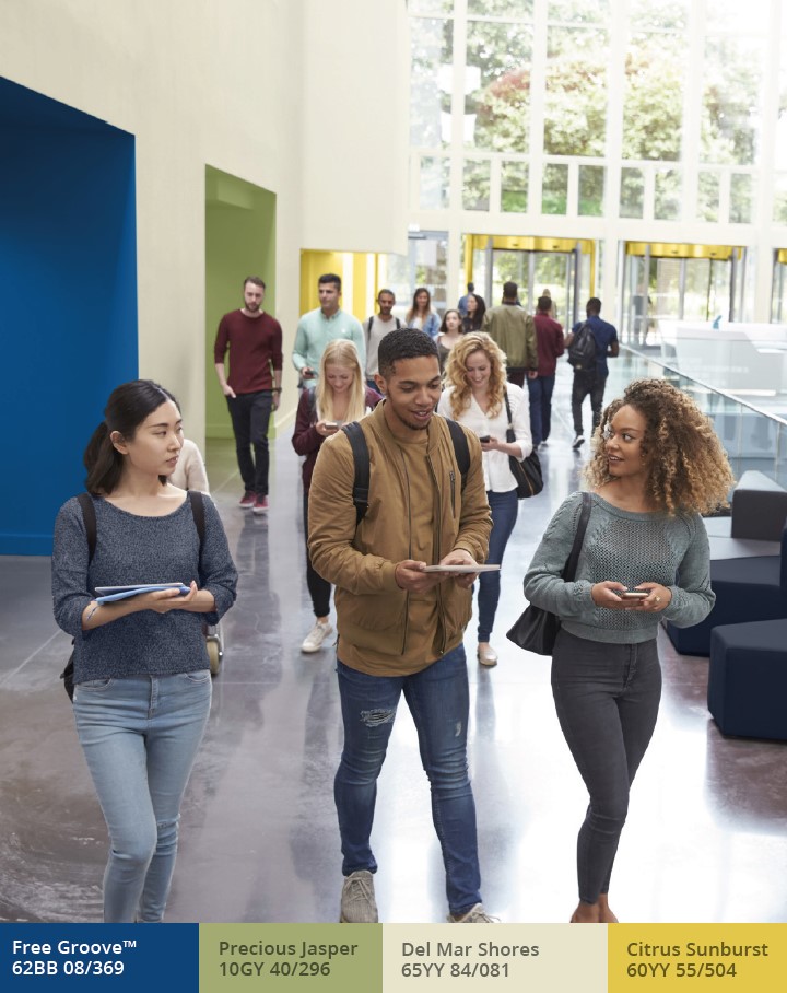 Students walking through an entrance hall with colourful alcoves and ochre pillars