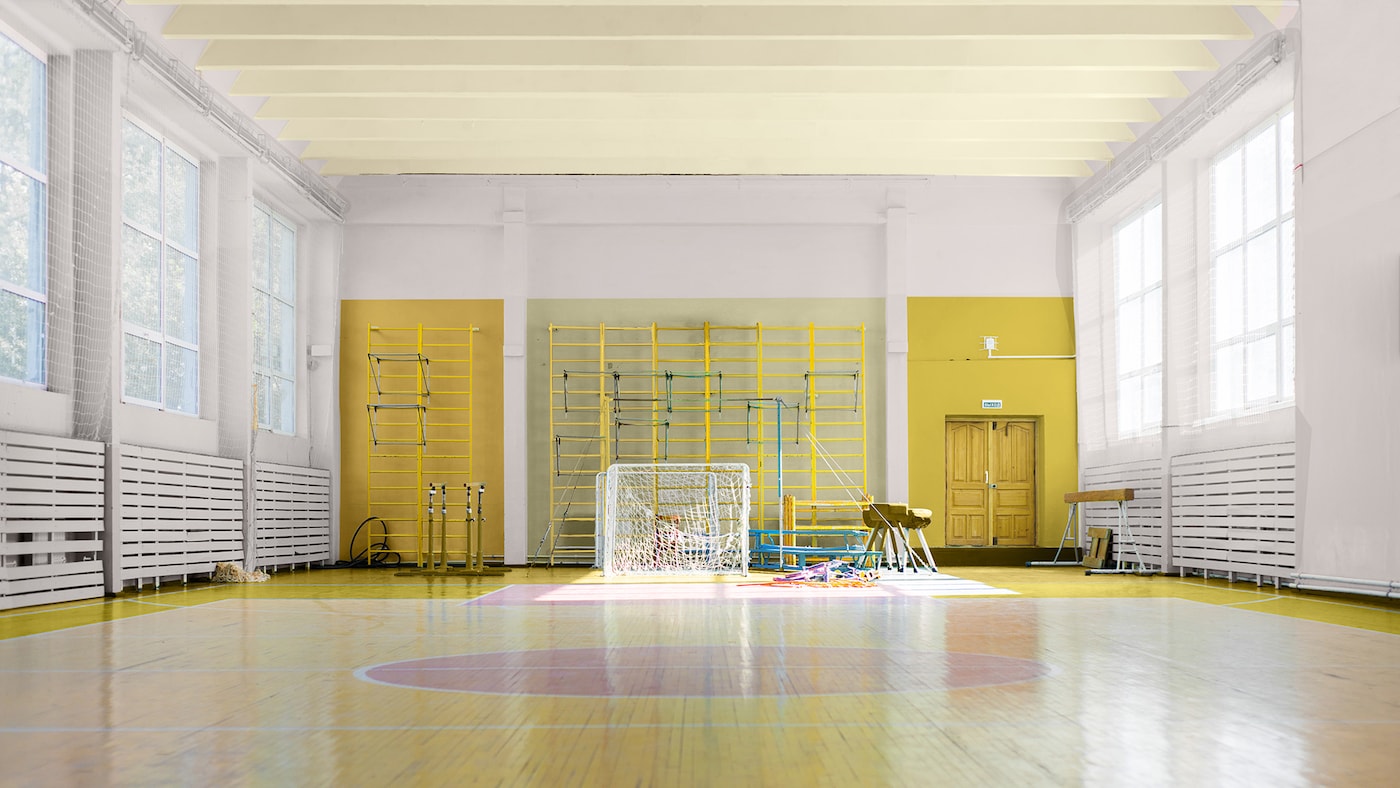 En sportshal med vægge malet i en blød lyserød farve. Den fjerneste endevæg er malet med en delt-væg effekt.