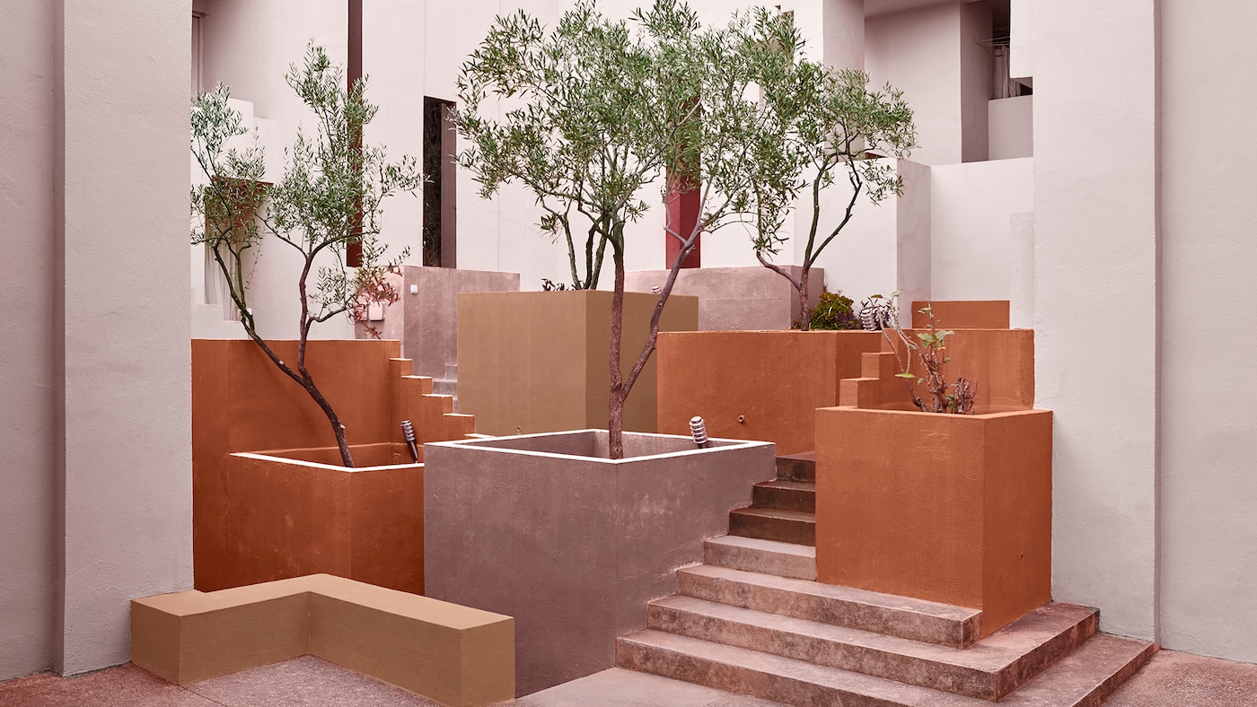 Et hotel eksteriør med plantekasser i træ malet i forskellige varme jordfarver – fra lyserød til terrakotta. 