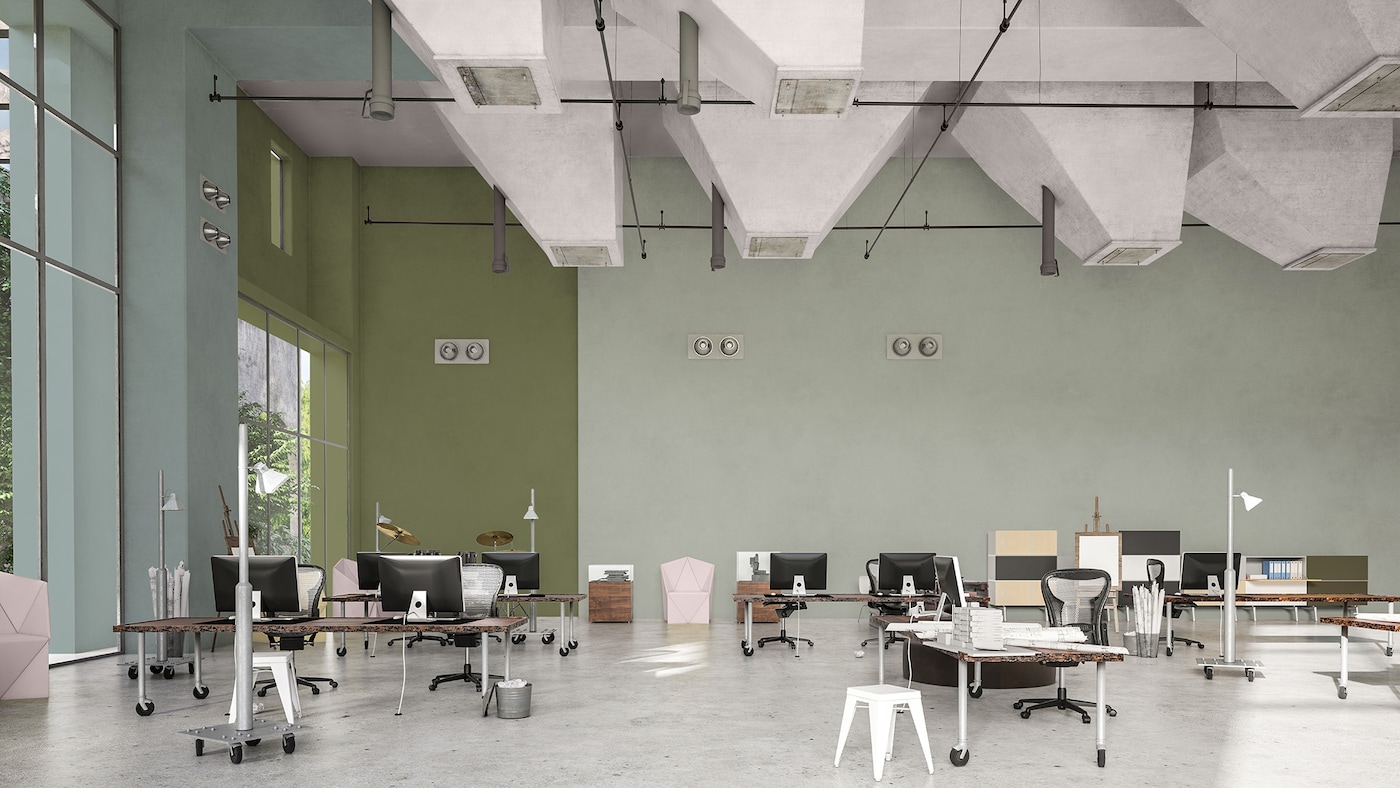 Et åbent kontor med en del af bagvæggen malet i mørkegrøn og resten af væggen malet i en lys pastelgrøn