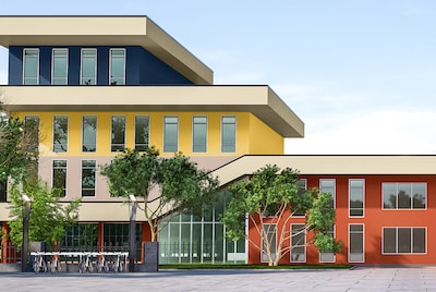 The exterior of a school brightly painted in yellow, blue and orange colours