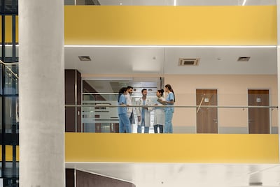 Nurses and Doctors talking in a healthcare building with levels painted bright yellow