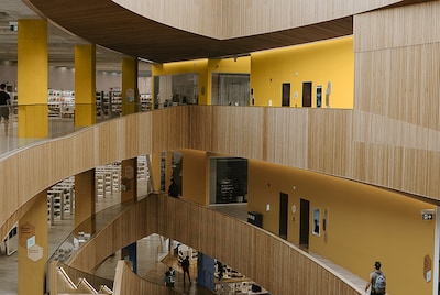 A modern library space over a few level. Yellow walls stand out from the wooden paneling