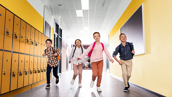 4 kinderen met rugzak lopend lachend door de schoolgang