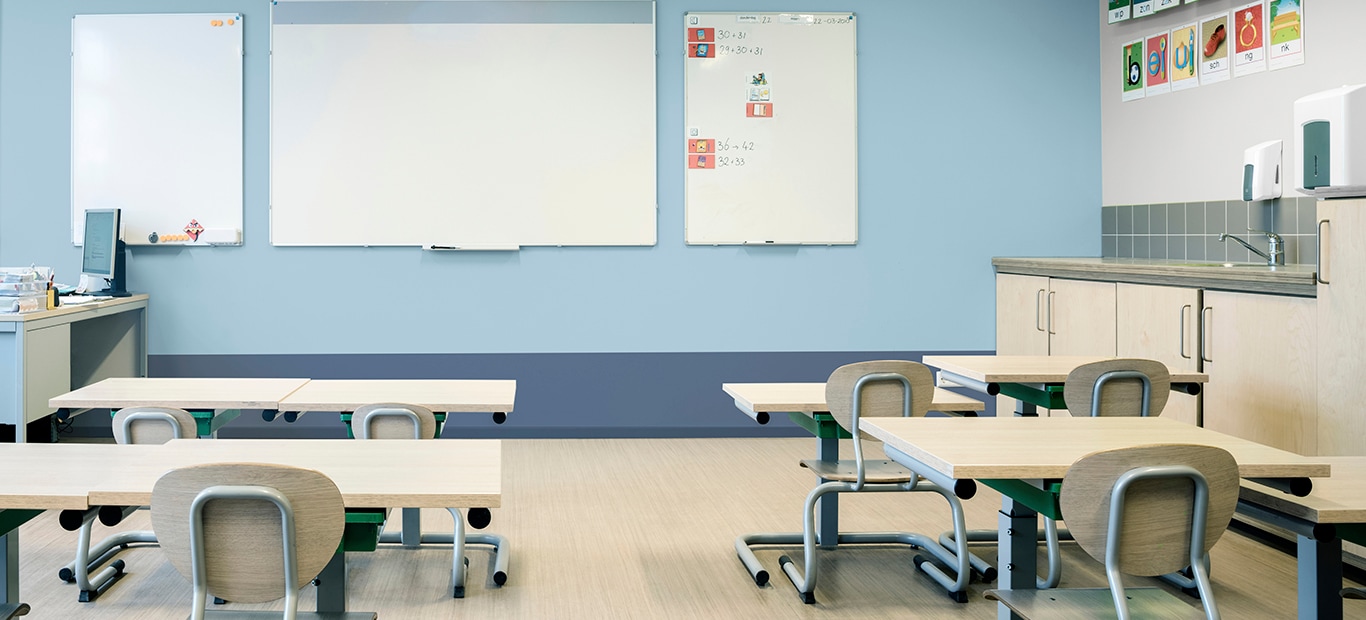 klaslokaal met banken en stoelen en whiteboard vooraan