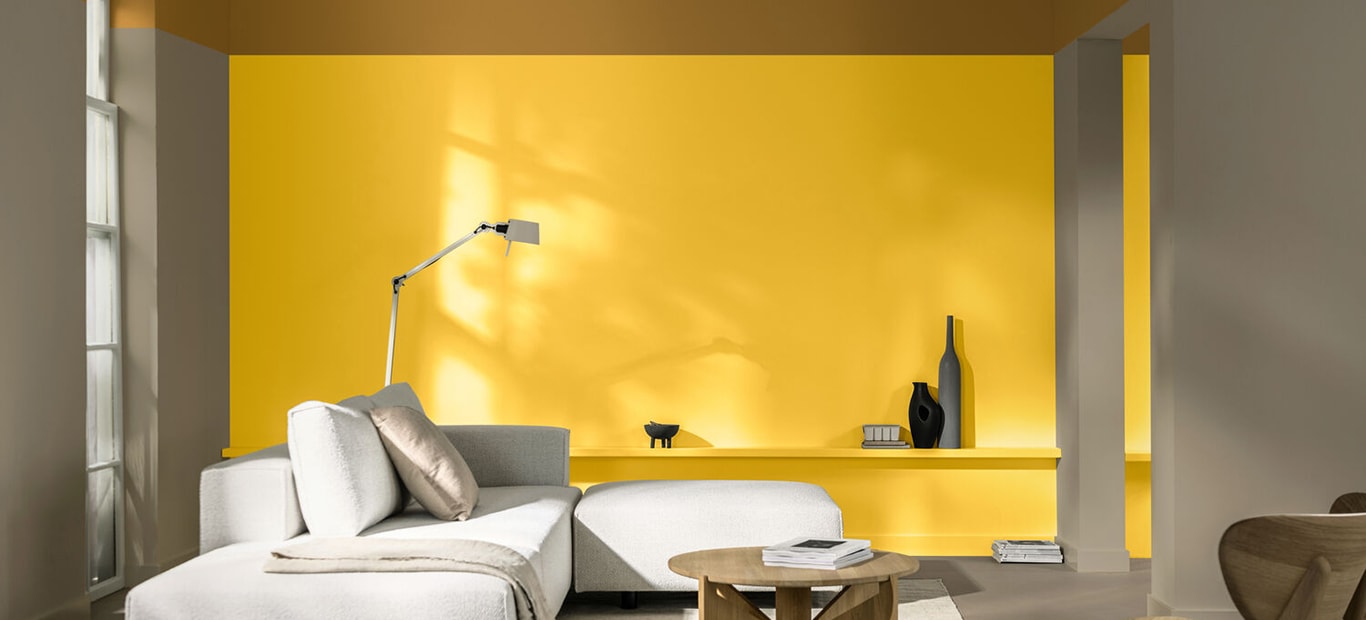 Salon met een muur in de gele kleur True Joy en een beige zetel