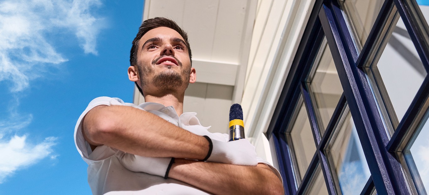 Maler streicht einen Fensterstock im Außenbereich